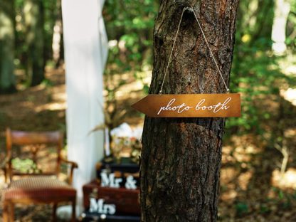 Drewniany drogowskaz na drzewie z napisem "photo booth"