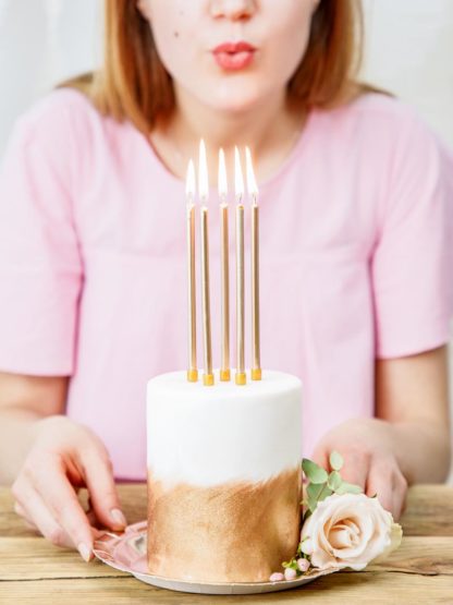 Złote, długie świeczki na torcie urodzinowym