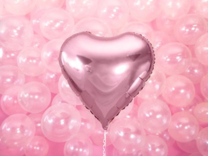 Różowy balon w kształcie serca na tle przezroczystych balonów