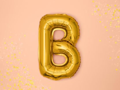 Złoty balon foliowy w kształcie litery B na różowym tle