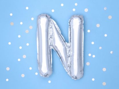 Srebrny balon foliowy w kształcie litery N na niebieskim tle