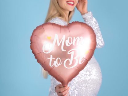 Kobieta w ciąży z różowym balonem foliowym w kształcie serca