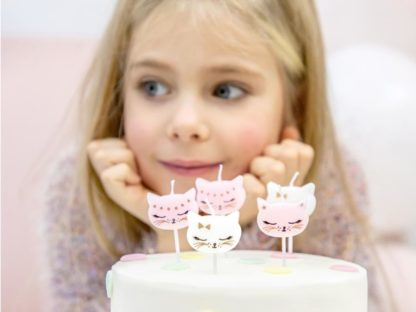 Dziewczynka z tortem i świeczkami w kształcie kotków