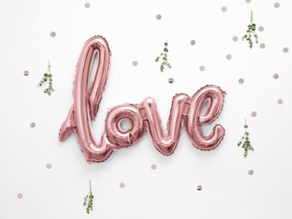 Różowe złoto balon w kształcie napisu "love" na tle konfetti