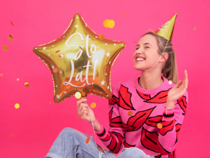 Kobieta ze złotym balonem foliowym na urodzinach