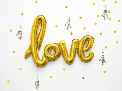 Złoty balon w kształcie napisu "love" na tle konfetti