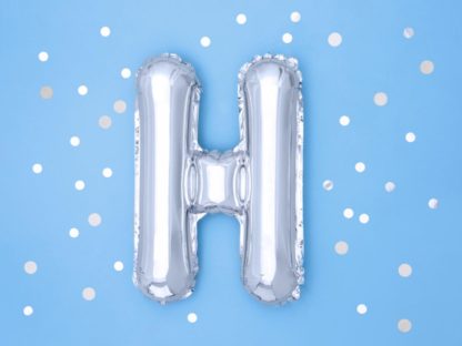 Srebrny balon foliowy w kształcie litery H na niebieskim tle