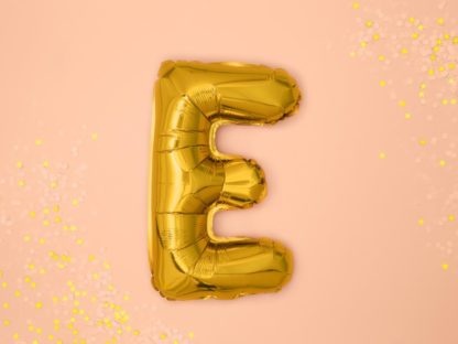 Złoty balon foliowy w kształcie litery E na różowym tle