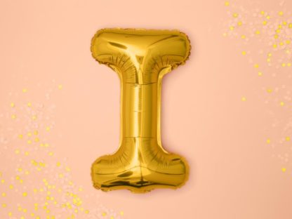 Złoty balon foliowy w kształcie litery I na różowym tle