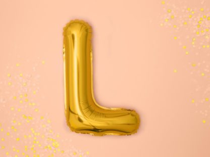 Złoty balon foliowy w kształcie litery L na różowym tle
