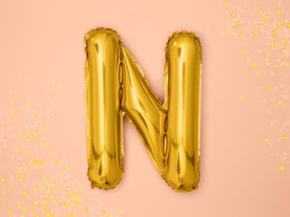 Złoty balon foliowy w kształcie litery N na różowym tle