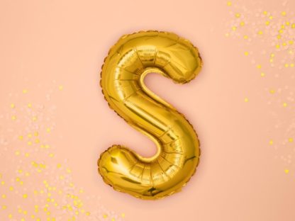 Złoty balon foliowy w kształcie litery S na różowym tle