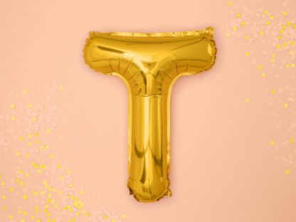 Złoty balon foliowy w kształcie litery T na różowym tle