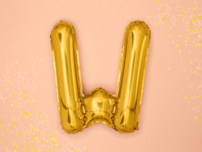 Złoty balon foliowy w kształcie litery W na różowym tle